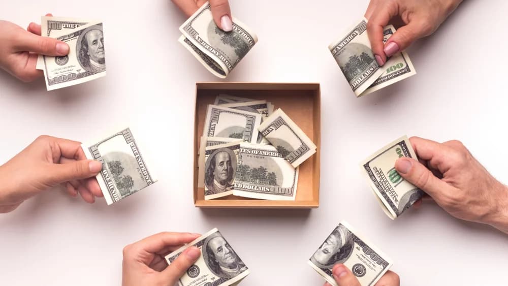Hands contributing money to a shared box