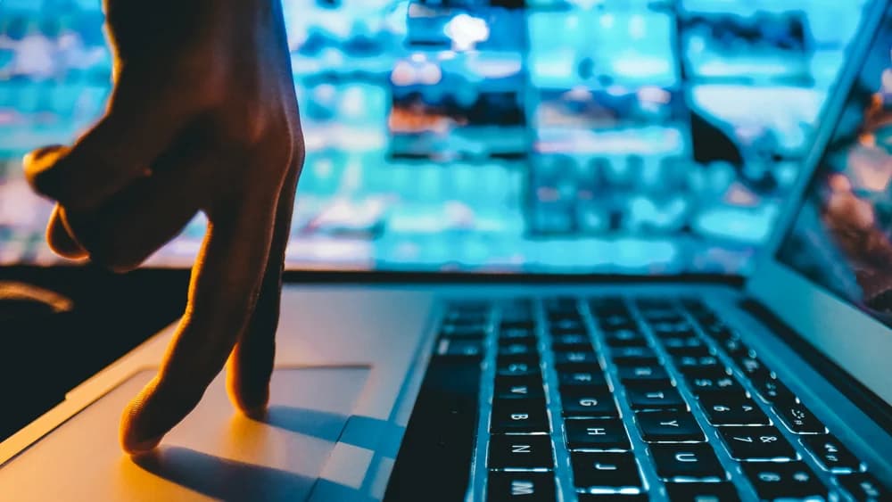 Hand above a laptop keyboard in blue light