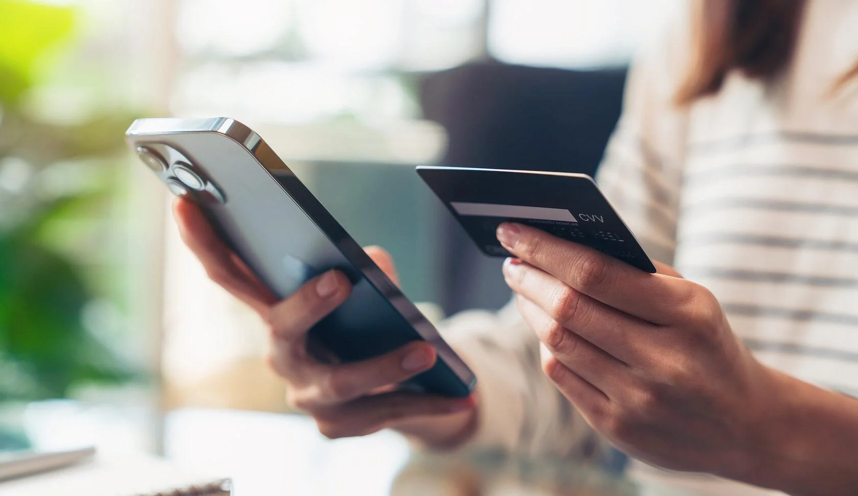 A person holding a smartphone and payment card